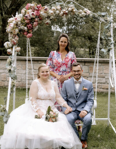 Braut und Bräutigam posieren mit Mandy Römer für ein Foto auf einer Schaukel
