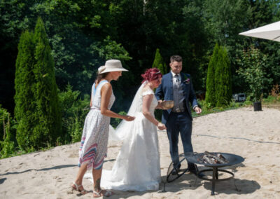 Braut, Bräutigam und Mandy Römer stehen vor der Feuerschale beim Feuerritual.